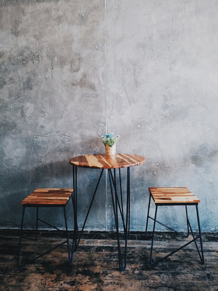 A minimalist wooden table with stools and a concrete wall background, ideal for modern interiors.